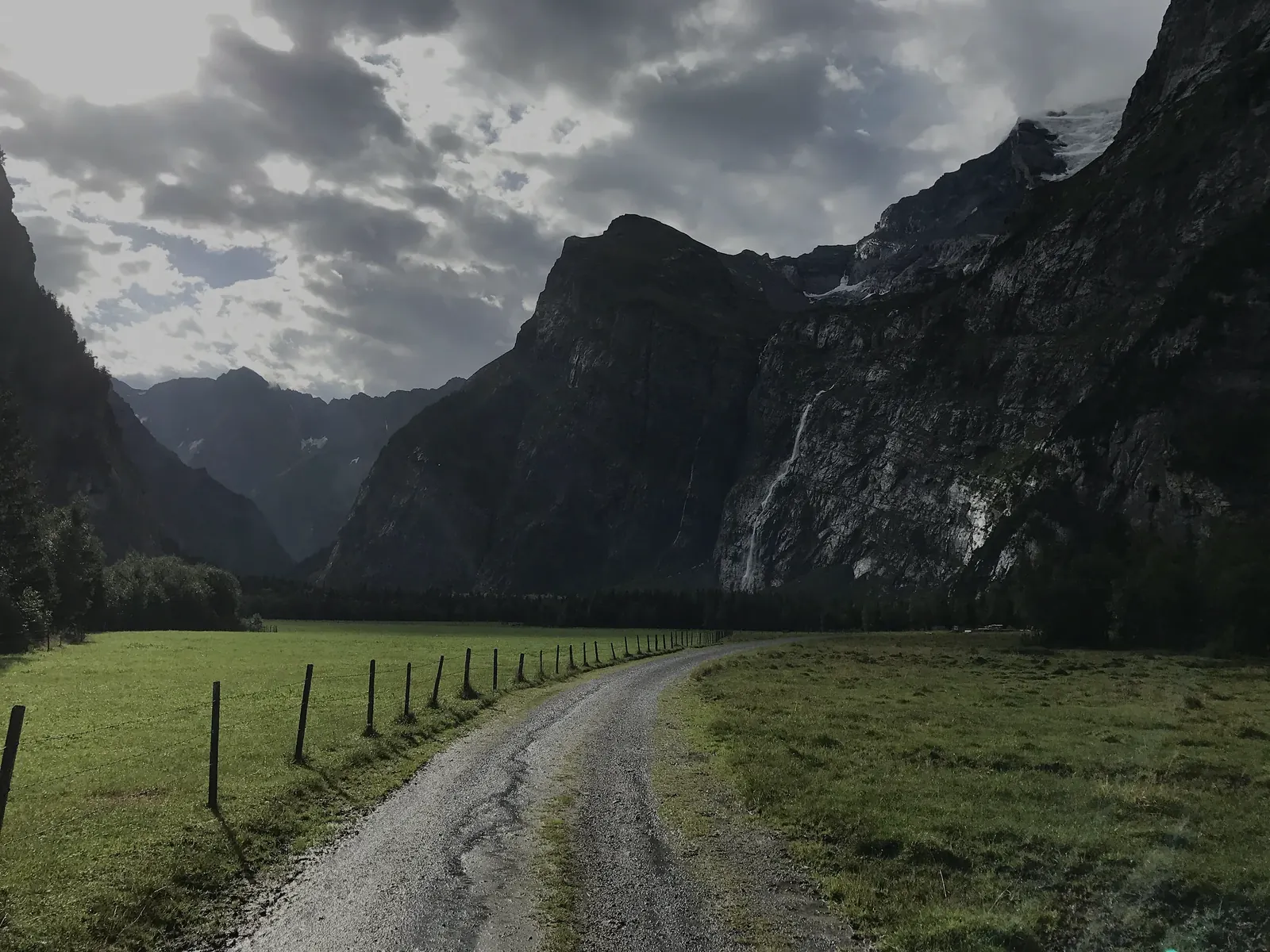 Die Naturstrasse im Talboden unter Regenwolken
