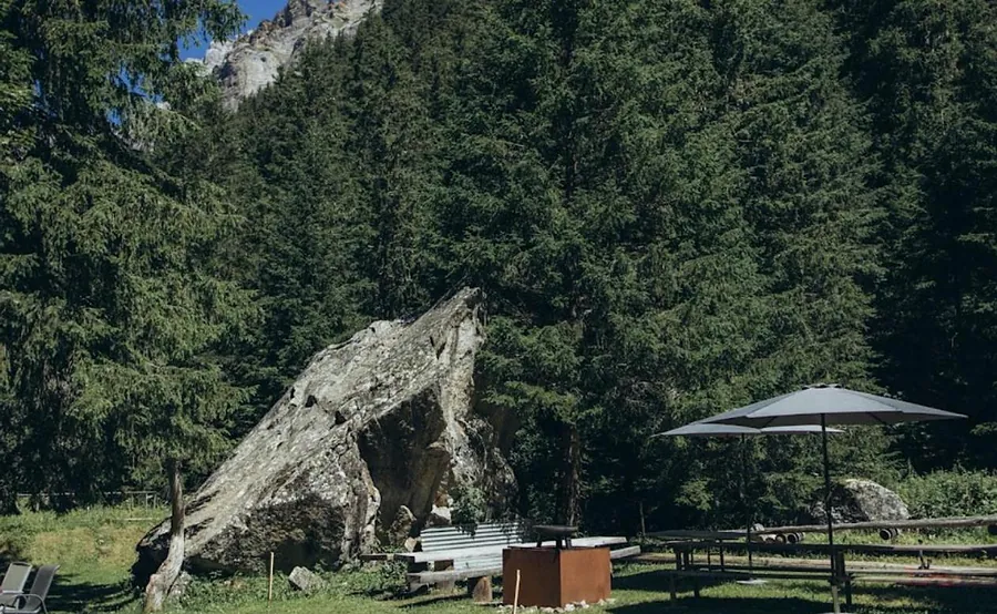 Feuerschale und Sonnenschirme vor dem grossen Felsblock beim Haus