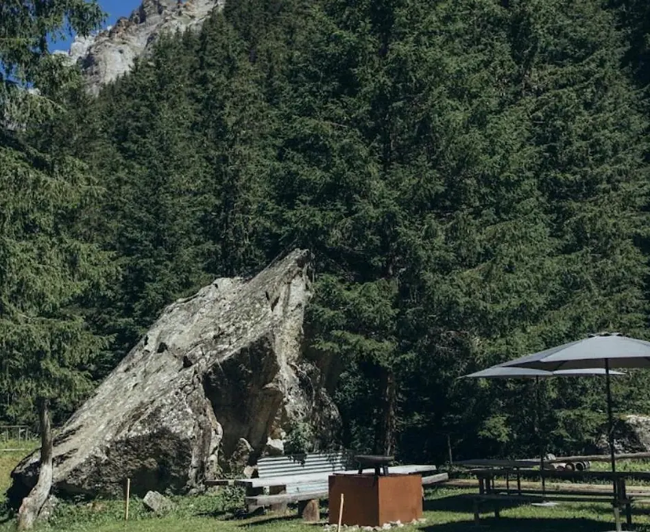 Feuerschale und Sonnenschirme vor dem grossen Felsblock beim Haus