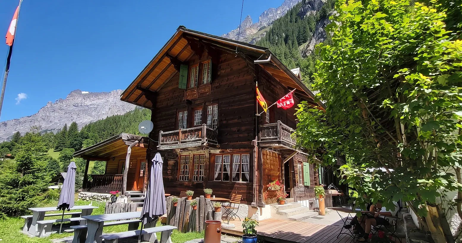 Die Giebelseite des Berghotel Gasterntal mit Fahne, dahinter die Berge